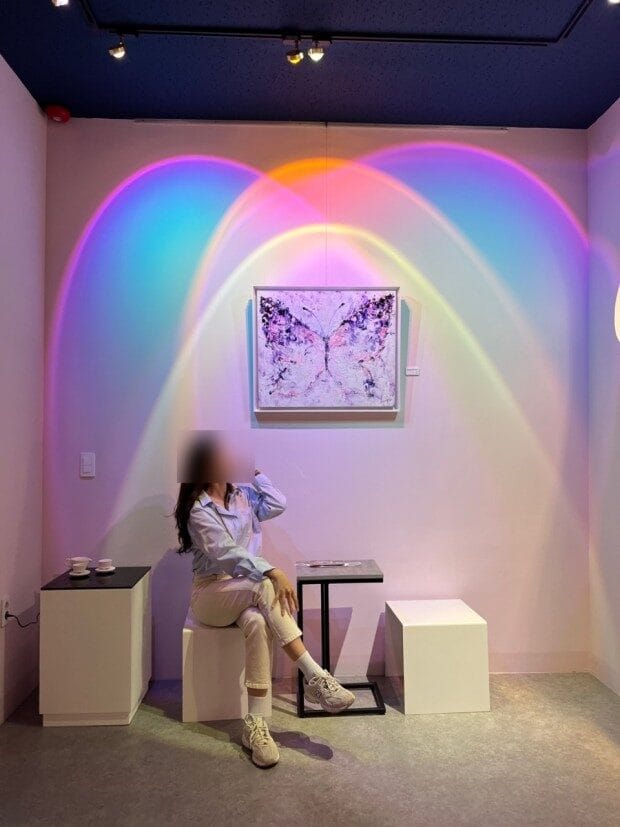무지개 조명으로 연출된 포토존에 앉은 관람객